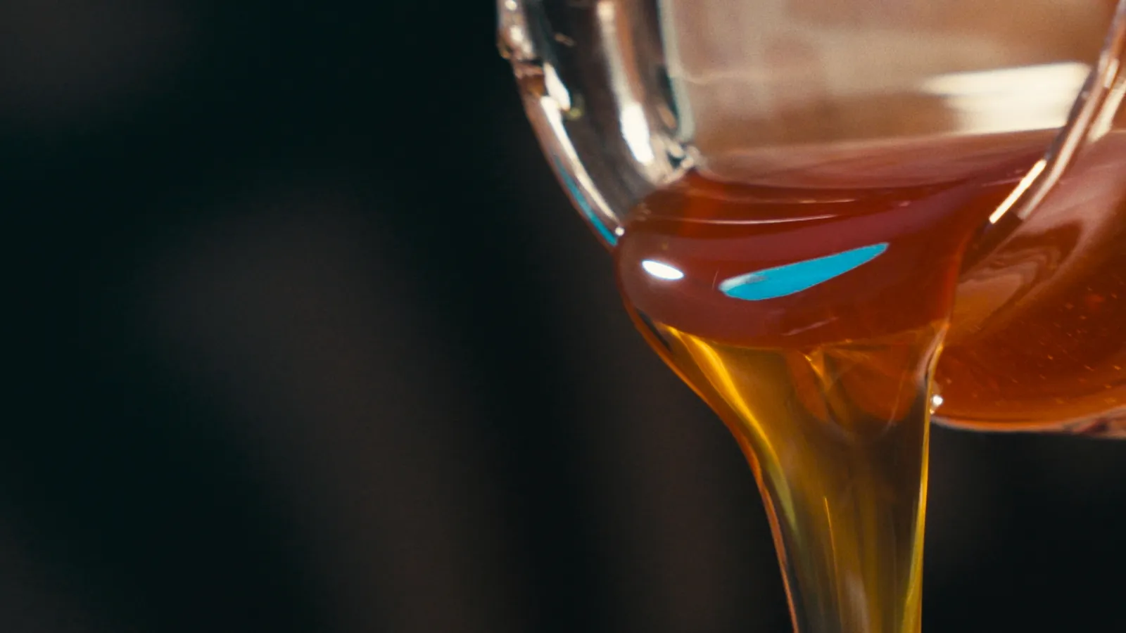Amber honey poured from a glass jug