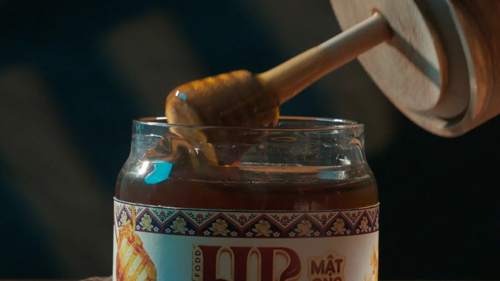 A honey dipper lifted from a brocade-labelled jar