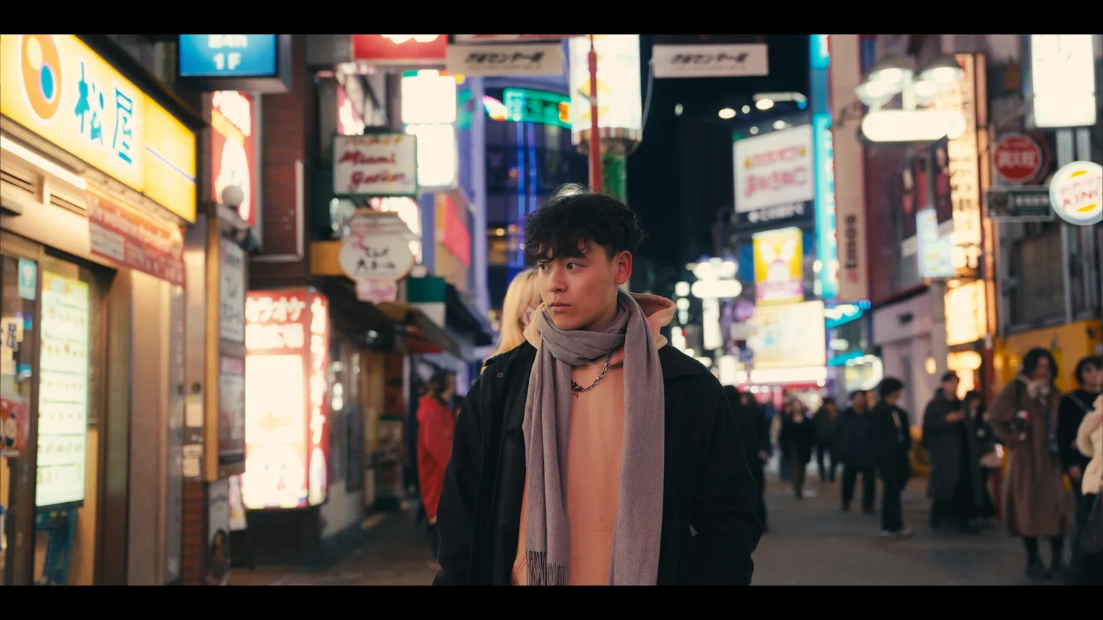 A traveller in a scarf on a neon-lit Shinjuku street