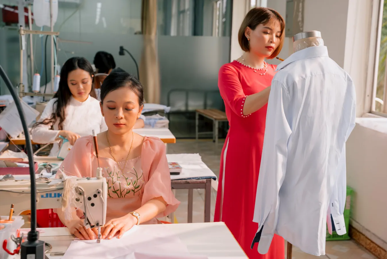 Fitting a white shirt on the mannequin, in a red áo dài